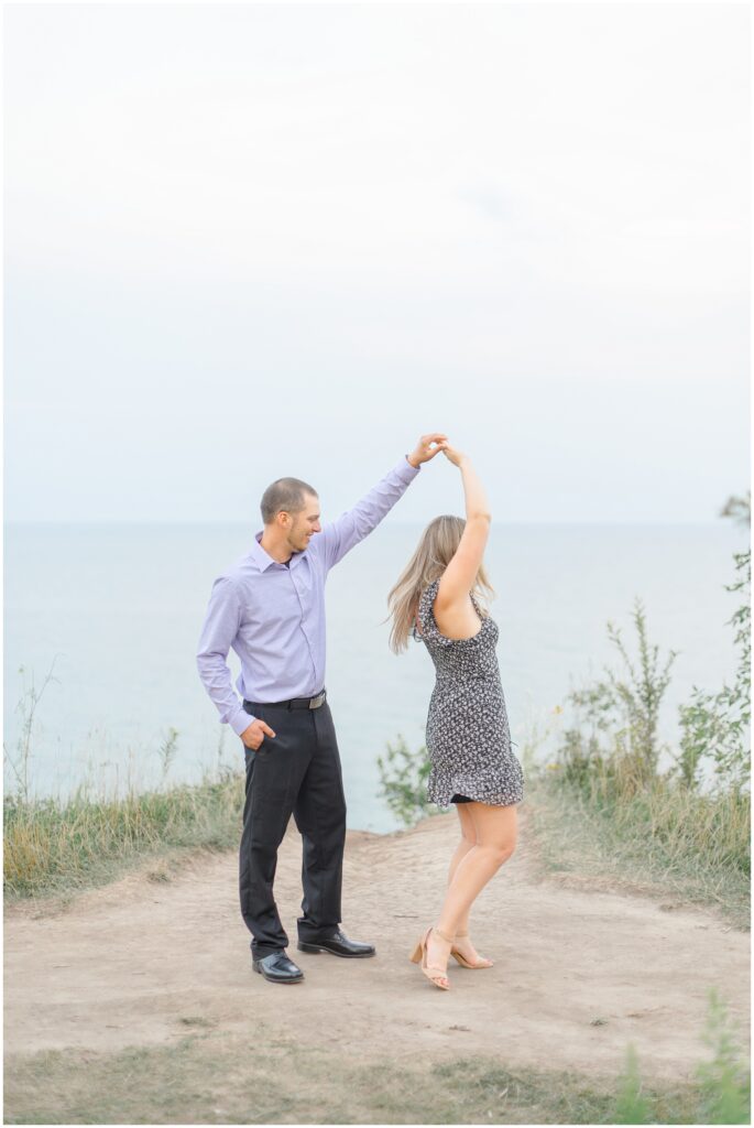 Groom spinning bride with Lake Michigan in the background for their lion's den gorge engagement session.